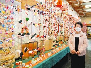 不用な着物などで作られた華やかなつるし飾りと、高橋さん＝松阪市の道の駅「飯高駅」で