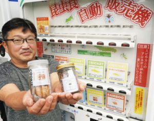 昆虫食の自動販売機を紹介する竹内さん＝木曽町開田高原の信州霧しなで