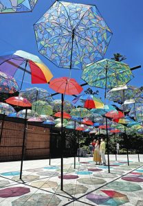 カラフルな傘が揺れ、青空や石畳を彩る「アンブレラスカイ」＝袋井市の法多山尊永寺で