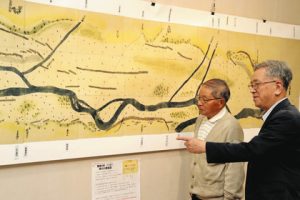江戸時代の梓川を描いた絵図を紹介する長岡さん（左）ら＝松本市梓川アカデミア館で