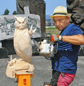 チェーンソーでフクロウの木像を彫る音琴和彦さん＝南砺市の道の駅井波で
