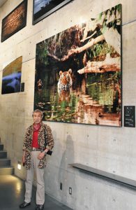 作品の前で野生動物の撮影の楽しさを語る吉野信さん＝高岡市のミュゼふくおかカメラ館で