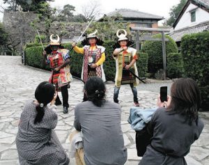 武将になりきり、写真撮影に応じる甲冑着付け体験の参加者たち＝松阪市殿町の御城番屋敷で