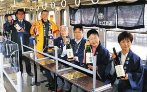 地酒電車の車内で自慢の日本酒をアピールする蔵元たち＝彦根市古沢町で