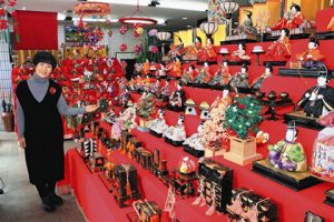 店内にずらりと並んで訪れた人を楽しませるひな人形と増田さん＝敦賀市相生町で
