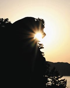 太陽をくわえたように見える獅子岩＝熊野市井戸町で