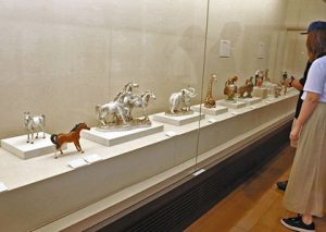 馬やキリンなどをモチーフにしたセトノベルティが並ぶ展示＝瀬戸市蔵所町の瀬戸蔵ミュージアムで