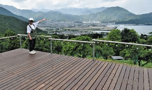 木製デッキのテントサイトからの眺めを紹介する笠松さん＝尾鷲市向井の「おわせむかい農園」で
