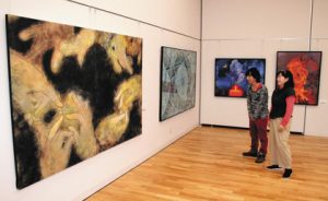 仏様の手が軟らかな線で描かれた戸谷さんの日本画（左）。個性あふれる現代美術作品がそろう＝松本市美術館で