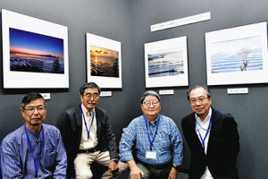 ４人が競作した熊本県の御輿来（おこしき）海岸の作品の前で（左から）磯貝さん、吉田さん、菱田さん、高木さん＝名古屋市中区栄１の富士フイルムフォトサロン名古屋で