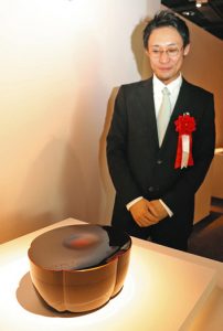 大賞を受けた新井寛生さんと作品「乾漆蒔絵箱　夜梅」＝金沢市広坂のしいのき迎賓館で