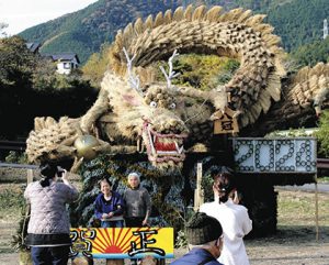 来年の干支の辰にちなんだ竜の前で、年賀状の写真用に撮影する人たち＝６日、島田市大代で