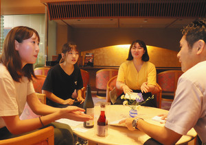 旅館の担当者（右）に新商品をＰＲする学生たち＝七尾市・和倉温泉で