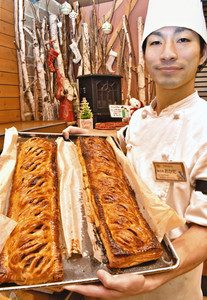焼きたてのアップルパイを手にする岡田さん。切り分けて店頭に並べる＝松本市並柳で