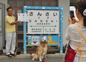 年齢看板を使って愛犬と記念撮影する家族連れ＝長野市のＪＲ三才駅で