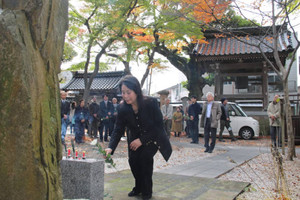 墓碑に献花して徳田秋声を追悼する参列者たち＝金沢市材木町の静明寺で