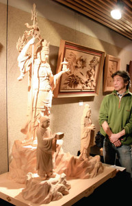 制作した毘沙門天三尊像を紹介する藤崎秀平さん＝南砺市北川で