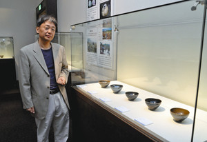 天目茶碗ばかりが並ぶ会場と長江さん＝瀬戸市美術館で