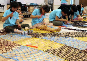カラフルな糸で漁網を編む現代文化コースの学生たち＝豊橋市の愛知大で